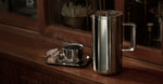 Stainless steel coffee press and cup on a wooden surface